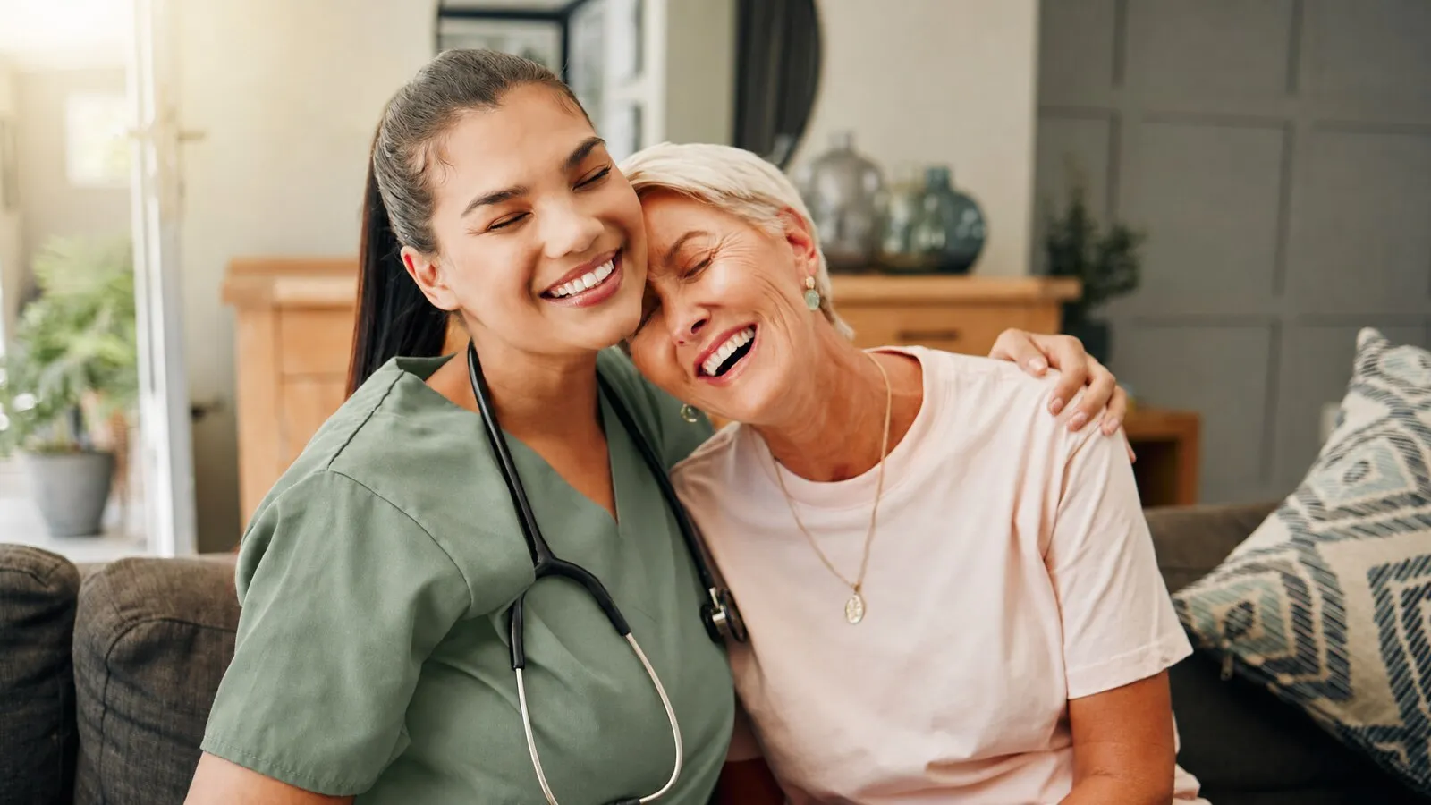 Carer and older woman sharing a warm moment on the couch
